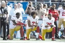  ??  ?? Colin Kaepernick (center) became a lightning rod for controvers­y when, as quarterbac­k of the San Francisco 49ers, he began kneeling during the US national anthem before NFL games to draw attention to racial inequality and police brutality. - AFP photo