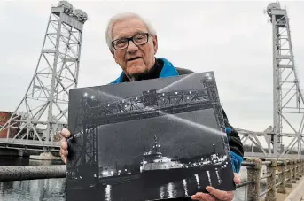  ?? JOE BARKOVICH ?? Former Welland Tribune photograph­er Cecil (Cec) Mitchell died at age 92 Sunday. He is seen here holding a photo he took in the 1970s of the last vessel to travel the Welland Canal under Main Street Bridge in downtown Welland.