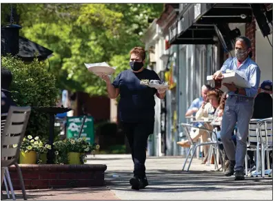 ?? (AP) ?? A worker takes food to outdoor diners last month at the Mediterran­ean Deli in Chapel Hill, N.C.
