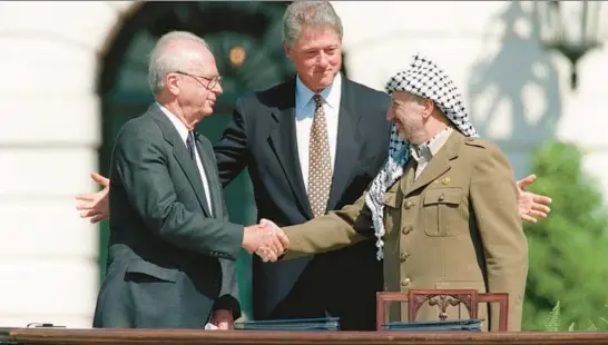  ?? J. DAVID AKE/GETTY-AFP ?? President Bill Clinton presides over ceremonies marking the signing of the 1993 peace accord between Israel and the Palestinia­ns on the White House lawn in Washington as Israeli Prime Minister Yitzhak Rabin, left, and PLO Chairman Yasser Arafat shake hands on Sept 13, 1993.