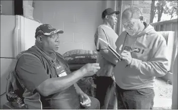  ??  ?? AT THE FOODSHARE food drop on Marshall Street in Hartford, Brice signs in Alejandro Perez, right. The twice-monthly food program sees anywhere from 60 to 200 people.