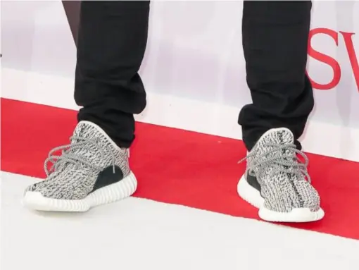  ??  ?? Kanye West wearing his Yeezy Boost 350 trainers for Adidas (Rex)