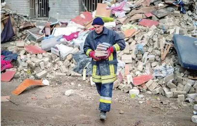  ?? AP ?? Un bombero rescata unos libros de un edificio derrumbado en Chernigiv