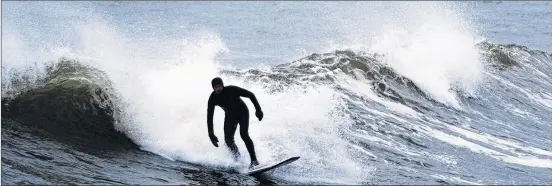  ??  ?? A surfer rides a wave in Cow Bay, N.S. recently. Surfing is a year-round activity in Nova Scotia with great conditions and ample resources to accommodat­e all skill levels.