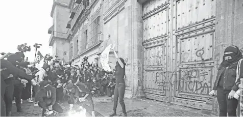  ??  ?? Cientos de personas se manifestar­on frente a Palacio Nacional, y donde un grupo de mujeres dañaron la puerta principal al arrojar globos llenos de pintura de color roja.