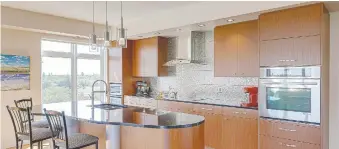  ??  ?? Redl World Class Kitchens brought the homeowners’ dream to reality. The suite’s sleek mahogany cabinets are complement­ed by a textured stainless steel backsplash, gleaming black granite counters and a sculpted island.