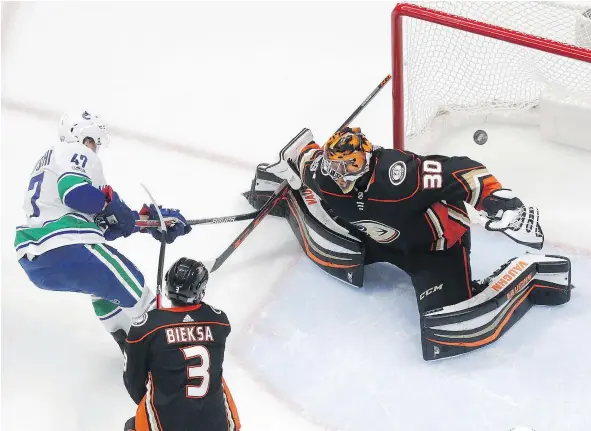  ?? — THE ASSOCIATED PRESS ?? Vancouver Canucks winger Sven Baertschi scores on former teammate Ryan Miller as Kevin Bieksa, another former Canuck, looks on Thursday at the Honda Center in Anaheim, Calif. It was Vancouver’s only goal in a 4-1 defeat to the Ducks.