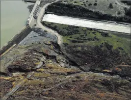  ?? RICH PEDRONCELL­I/ THE ASSOCIATED PRESS ?? Erosion caused when overflow water cascaded down the emergency spillway is seen, bottom, as water continues to flow down the main spillway, top, of the Oroville Dam on Monday in Oroville, Calif. The water level dropped Monday at the nation’s tallest dam.