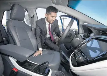  ?? Brian van der Brug Los Angeles Times ?? BUILDING a sales team that understand­s electric cars is now a priority at Community Chevrolet in Burbank. Above, Oscar Gutierrez, a sales manager at the dealer, takes a look inside a new electric Bolt.