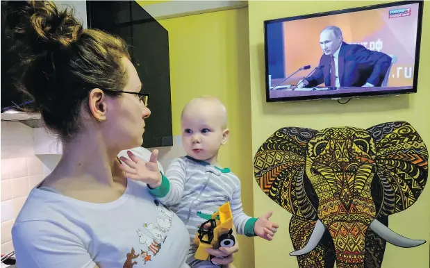  ?? YURI KADOBNOV / AFP / GETTY IMAGES ?? A woman watches a TV broadcast of Russian President Vladimir Putin’s annual press conference in Moscow on Thursday.