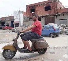  ?? — AFP ?? A Tunisian rides an old scooter in the Tunis district of Ettadhamen ahead of the September 15 presidenti­al election.