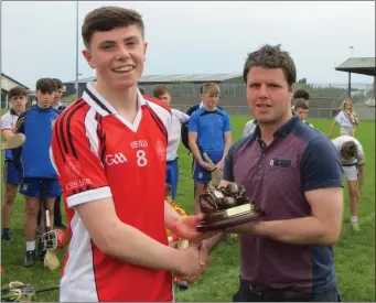  ??  ?? New Ross C.B.S. captain Colum Feeney collecting the trophy from Tadhg Doran of the Leinster Post Primary Schools committee.