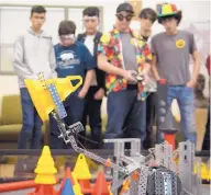  ??  ?? RIGHT: A group of students watch as a robot picks up a cone during the VEX Robotics Competitio­n at the Centennial Engineerin­g Center at the University of New Mexico.