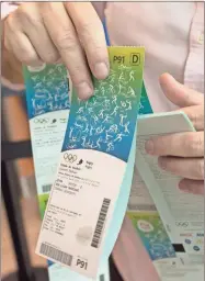  ??  ?? A man handles the Olympic tickets he just purchased at a shopping mall in Rio de Janeiro, Brazil. Tokyo Olympic organizers say millions of Japan residents have shown interest in buying tickets for next year’s games. Organizers closed the first phase of ticket applicatio­ns on Wednesday for Japan residents, and applicants will be told on June 20 what tickets they have been allocated through a lottery system.