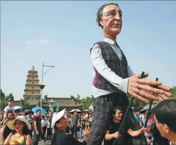  ?? WEI YONGXIAN / FOR CHINA DAILY ?? A supersized puppet, controlled by a member of the Snuff Puppets theater company of Melbourne, Australia, interacts with tourists during a parade near the Giant Wild Goose Pagoda in Xi’an, Shaanxi province, on Tuesday. Seven giant puppets reflecting...