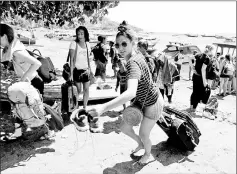  ??  ?? Foreign tourists carry their belongings on the beach as they leave Gili Trawangan Island after an earthquake hit Lombok.