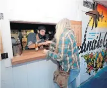  ?? JOHN MCCALL/SOUTH FLORIDA SUN SENTINEL ?? Bartender Sergio Gonzalez fist bumps a customer from the outdoor bar at Oceanside Gardens in Delray Beach on Jan. 24.