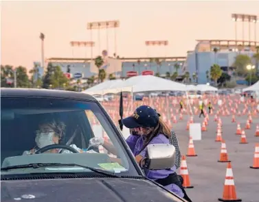  ?? PHILIP CHEUNG/THE NEW YORK TIMES ?? Maria Rivera gets a COVID-19 vaccine injection Thursday at Dodger Stadium. Los Angeles County officials say the call for testing has collapsed. Not long ago, the county was conducting over 350,000 tests weekly.