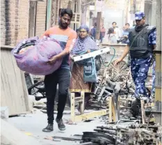  ?? IANS ?? ABOVE: People carry their possession­s from their homes under the shadow of the police after the riots in north-east Delhi’s Shiv Vihar.
RIGHT: United Sikh India volunteers distribute food material and daily-use items to riot victims at north-east Delhi’s Old Mustfabad. |