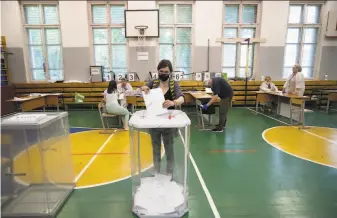  ?? Alexander Zemlianich­enko / Associated Press ?? A voter wearing a face mask to protect against the coronaviru­s casts her ballot at a school in Moscow. The Kremlin has repeatedly dismissed safety concerns about inperson voting.