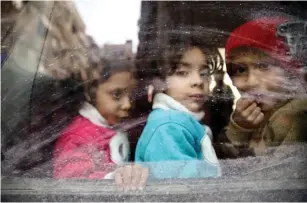  ?? (Bassam Khabieh/Reuters) ?? CHILDREN LOOK through a bus window yesterday during their evacuation from the besieged town of Douma, in Syria’s eastern Ghouta area.