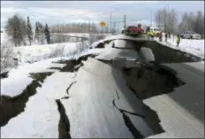  ?? MIKE DINNEEN - THE ASSOCIATED PRESS ?? A tow truck holds a car that was pulled from on an offramp that collapsed during a morning earthquake on Friday, in Anchorage, Alaska. The driver was not injured attempting to exit Minnesota Drive at Internatio­nal Airport Road. Back-to-back earthquake­s measuring 7.0 and 5.8 rocked buildings and buckled roads Friday morning in Anchorage, prompting people to run from their offices or seek shelter under office desks, while a tsunami warning had some seeking higher ground.