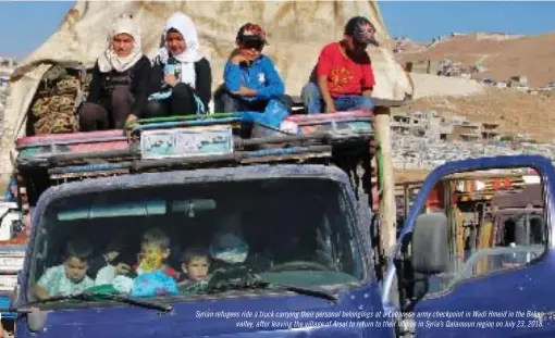  ??  ?? Syrian refugees ride a truck carrying their personal belongings at a Lebanese army checkpoint in Wadi Hmeid in the Bekaa valley, after leaving the village of Arsal to return to their homes in Syria’s Qalamoun region on July 23, 2018.