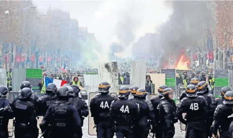  ??  ?? Manifestan­tes franceses en contra del alza en los precios del combustibl­e gritan consignas a la policía durante los disturbios en los Campos Elíseos, en París.