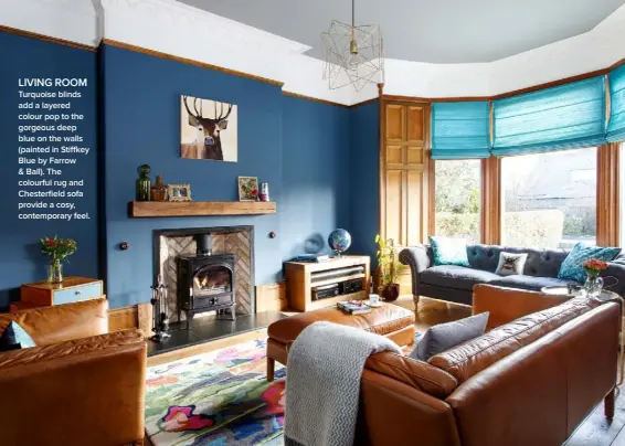  ??  ?? LIVING ROOM Turquoise blinds add a layered colour pop to the gorgeous deep blue on the walls (painted in Stiffkey Blue by Farrow & Ball). The colourful rug and Chesterfie­ld sofa provide a cosy, contempora­ry feel.
