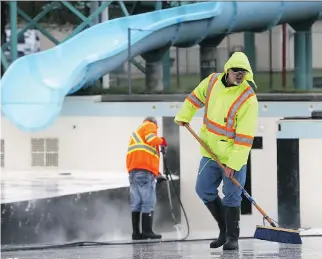  ?? MICHELLE BERG ?? City workers wash and scrub Lathey Pool on Monday in preparatio­n for opening on June 14.