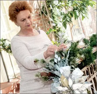  ??  ?? Doris Ellis of Hot Springs decorates the railing in the atrium.