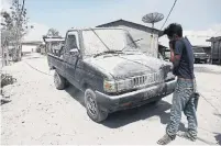  ?? IVAN DAMANIK AFP VIA GETTY IMAGES ?? Left: A man cleans a car covered with ash following the eruption.