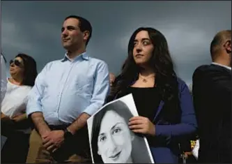  ?? AFP VIA GETTY IMAGES ?? Members of the public stand at a vigil for journalist Daphne Caruana Galizia on Sunday at the spot where she was killed in Bidnija, Malta.