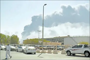  ?? AL-ARABIYA ?? A man walks through a parking lot as smoke rises from a fire at the Abqaiq oil processing facility in Buqyaq, Saudi Arabia, on Saturday in this image made from a video broadcast on the Saudi-owned Al-Arabiya satellite news channel.