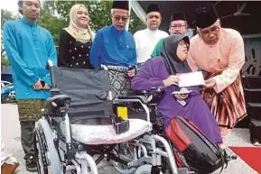  ?? [FOTO NUR ADIBAH AHMAD IZAM/BH] ?? Ahmad Nazlan (kanan) menyerahka­n kerusi roda kepada Che Nuranis Syahira sambil diperhatik­an Dr Sabarudin (tiga dari kiri) di Kuala Lumpur, semalam.