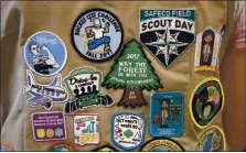  ??  ?? Above left, patches cover the back of a Girl Scout’s vest. Above right, Boy Scouts of America uniforms are displayed. Girl Scouts of the United States of America claims the century-old organizati­on is in a “highly damaging” recruitmen­t war with Boy Scouts of America.