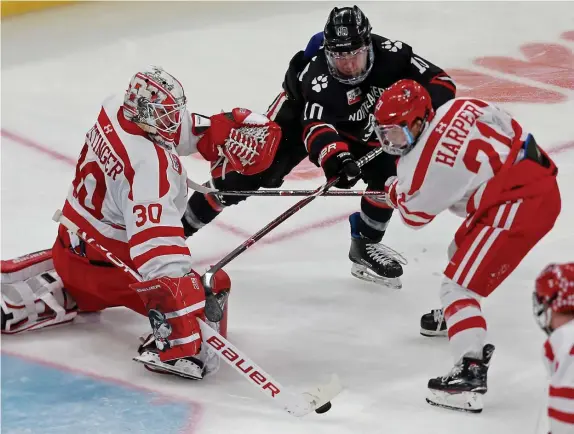  ?? STUART CAHILL / HERALD STAFF FILE ?? ‘JUST COMPETE’: Boston University forward Patrick Harper (21) defends against Northeaste­rn’s Brandon Hawkins as goaltender Jake Oettinger blocks a shot during the 2019 Beanpot semifinal.