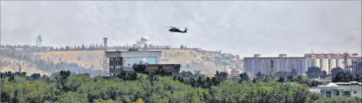  ?? AP ?? A US Black Hawk military helicopter flies over the city of Kabul in Afghanista­n on Sunday. The capital city was in the centre of the action throughout the day as Taliban fighters negotiated a peaceful transfer of power.