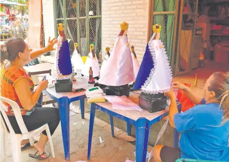  ??  ?? María Concepción Benítez (der.) y su nuera Yenny Fatecha trabajan intensamen­te en la preparació­n de las imágenes de la Virgen Milagrosa, vestida con sus mejores galas. Esperan superar la venta del año pasado.