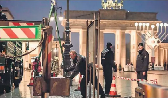  ?? CLEMENS BILAN / AFP ?? La policía alemana dispone obstáculos de hormigón para proteger de ataques la zona de la Puerta de Brandembur­go, en Berlín