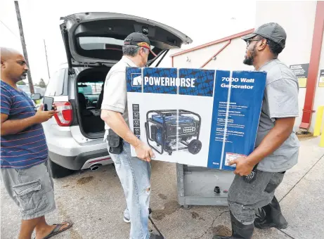  ?? Karen Warren / Houston Chronicle ?? Doug Beltran, center, and Johnathan Holmes, right, load a generator for a customer Friday at Northern Tool + Equipment in Stafford.