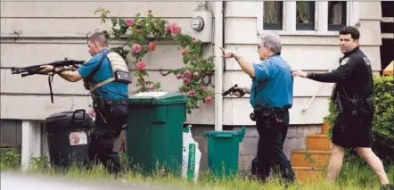  ?? Elaine Thompson Associated Press ?? POLICE SURROUND a house in Seattle’s University District near a cafe where a man shot five people in the first of two attacks.