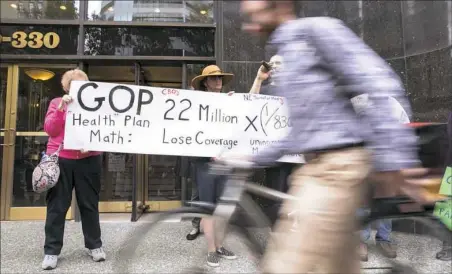  ?? Antonella Crescimben­i/Post-Gazette ?? Protesters carry signs Tuesday outside of U.S. Sen. Pat Toomey’s office on Grant Street, Downtown Pittsburgh.