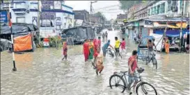  ?? PTI ?? People cross a waterlogge­d street during high tide in Kolkata on Thursday.