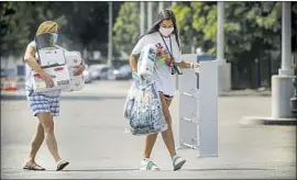  ?? Irfan Khan Los Angeles Times ?? RICHELLE MENESES, 52, left, helps her 18-year-old daughter, Sidney Meneses, move into her dormitory at Cal State Fullerton, the system’s largest college.