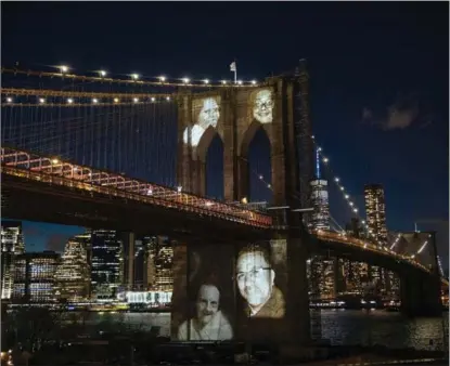  ?? KEVIN HAGEN / REUTERS ?? Images of COVID-19 victims are projected onto New York’s Brooklyn Bridge on March 14. The citywide death toll exceeds World War II, the Vietnam War, Hurricane Sandy and the Sept 11 attacks combined.