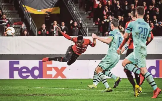  ??  ?? Penyerang Rennes, Ismaila Sarr (kiri) menanduk masuk gol ketiga mereka ketika pusingan keempat Liga Europa menentang Arsenal di Stadium Roazhon Park di Rennes, kelmarin.