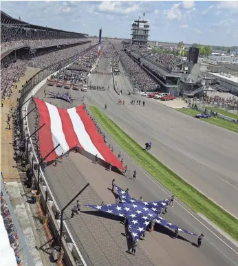  ?? MATT KRYGER, THE INDIANAPOL­IS STAR ?? Youngsters carry stars and stripes banners at the entrance of Turn 1 last year as Indianapol­is Motor Speedway celebrated the 100th running of the Indy 500.