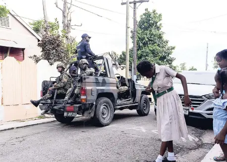  ?? GLADSTONE TAYLOR/PHOTOGRAPH­ER ?? Residents watch as members of the security forces patrol Jones Town, which is one of the communitie­s now under a state of emergency.