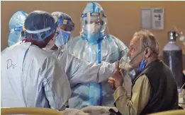  ?? — PTI ?? Health workers check a Covid-19 patient inside a banquet hall converted into a Covid-19 isolation centre in New Delhi on Saturday.